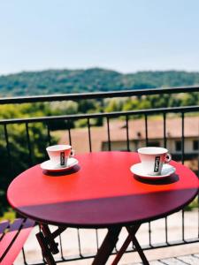 Duas chávenas de café numa mesa vermelha na varanda em Bianchi &Bianchi casa vacanza Laveno-Mombello em Laveno