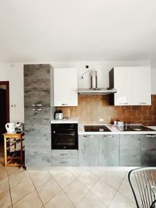 une cuisine avec des appareils électroménagers en acier inoxydable et des armoires blanches dans l'établissement Bianchi &Bianchi casa vacanza Laveno-Mombello, à Laveno-Mombello
