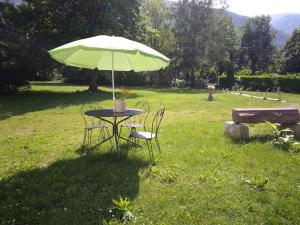 einen Tisch und Stühle unter einem Schirm auf einem Feld in der Unterkunft La dépendance in Luchon