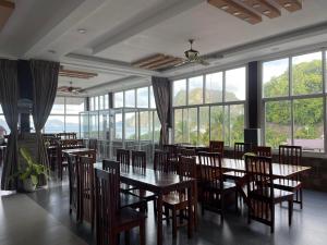 a dining room with tables and chairs and windows at El Nido Royal Palm Inn in El Nido