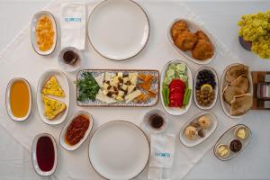 uma mesa branca com pratos de comida em La Luz Hotel & Spa Bozcaada em Bozcaada