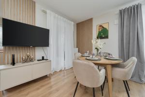 弗次瓦夫的住宿－Beautiful 3-Bedroom Apartment Gwiaździsta 18 by Renters，一间带桌子和平面电视的用餐室