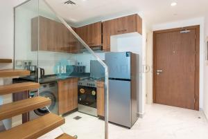 a kitchen with a stainless steel refrigerator and wooden cabinets at Classic 2 Bedroom In Oasis in Al Qurayyah