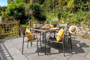 a table with yellow pillows and chairs on a patio at Luxury Town House - Apple Pie Luxury Escapes in Tavistock
