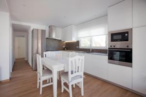 eine Küche mit weißen Schränken sowie einem weißen Tisch und Stühlen in der Unterkunft Acogedor apartamento junto al mar in Oliva