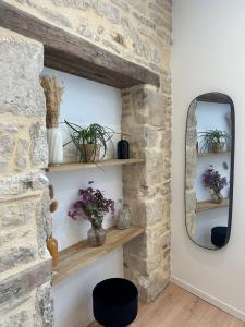 Habitación con pared de piedra con estanterías y espejo. en La Cabotte - Confort & Charme au Centre Historique - Balcon sur cour, en Dijon