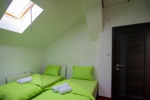 2 camas verdes en una habitación con ventana en Hostel Aurora, en Požarevac