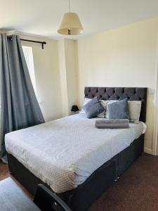 a bedroom with a large bed with blue pillows at DARTFORD CROSSING The BRIDGE PLACE - CONTRACTORS FAVOURITE in Kent