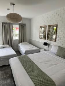 1 dormitorio con 3 camas y ventana grande en The Shamrock Hotel, en Toowoomba