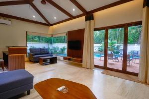 uma sala de estar com um sofá e uma mesa em Tropical villa by Happyinch em Saligao