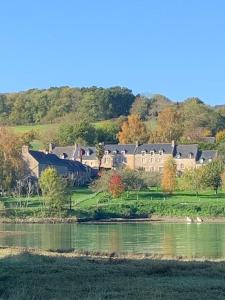 uma casa grande numa colina ao lado de um lago em La Vallée d'émeraude em Plouër-sur-Rance