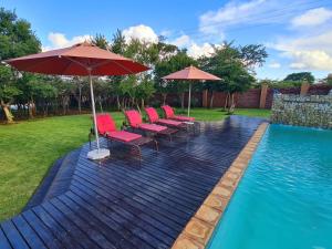 a group of chairs and umbrellas next to a pool at Gucci Manor Boutique Guesthouse in Polokwane