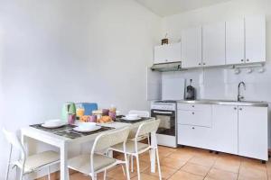 eine weiße Küche mit einem Tisch, Stühlen und einem Waschbecken in der Unterkunft Appartement beau confort in Saint-Fons