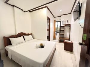 a bedroom with a large white bed and a television at Alocasia Hostel in El Nido
