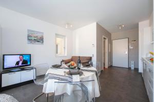 a white living room with a table and a television at Sunrise House - Happy Rentals in Lugano