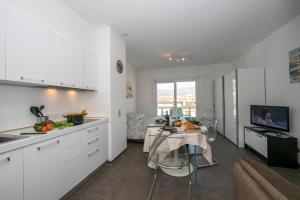 eine Küche mit weißen Schränken und einem Tisch im Zimmer in der Unterkunft Sunrise House - Happy Rentals in Lugano