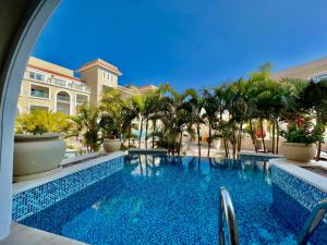 a swimming pool with palm trees and a building at KaiSol Romance Resort Sahl Hasheesh - Adults Only in Hurghada