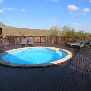 a swimming pool on a deck with two chairs at Kanaan, Mabalingwe in Mabula