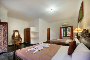 a bedroom with two beds with dolls sitting on them at Hotel Lumbung Sari Legian in Legian