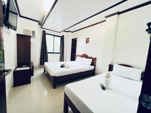 a hotel room with two beds and a television at Alocasia Hostel in El Nido