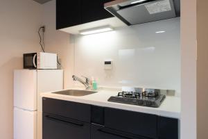 a kitchen with a sink and a white refrigerator at LUXE Minami Aoyama in Tokyo