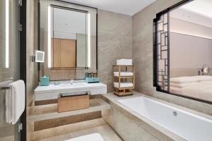 a bathroom with a tub and a sink and a bed at Doubletree By Hilton Suzhou Wuzhong in Suzhou