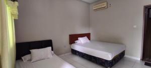 OYO 93051 Wisma Syariah Buloe في Enrekang: غرفة نوم صغيرة بسريرين ونافذة