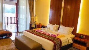 a hotel room with a large bed with flowers on it at Agro Hotel Bintan in Telukbakau