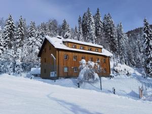 un gran edificio de madera con árboles en la nieve en APARTMENTS ROGLA JURGOVO - Ski in Ski out, en Lukanja