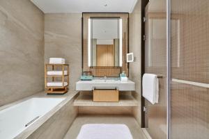 a bathroom with a tub and a sink and a mirror at Doubletree By Hilton Suzhou Wuzhong in Suzhou