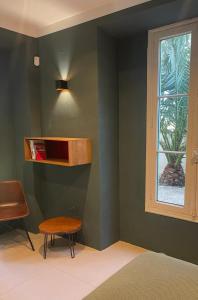 イエールにあるResidence Alouettesの緑の壁の客室で、テーブルと窓が備わります。