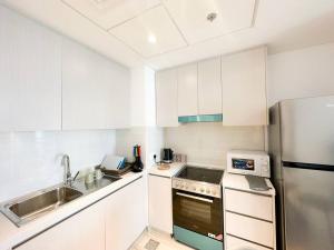 uma cozinha com armários brancos e um frigorífico de aço inoxidável em Casa Dei Ricordi 620WB8 em Abu Dhabi