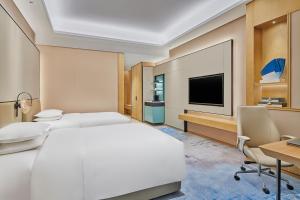 蘇州市にあるDoubletree By Hilton Suzhou Wuzhongのベッド、デスク、テレビが備わるホテルルームです。