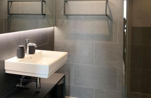 a bathroom with a white sink and a shower at Luxuriöse Berg-Ferienwohnungen-Andermatt in Andermatt