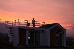 un hombre de pie en la parte superior de una casa con la puesta de sol en Northland Pai, en Pai