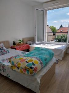 two beds in a room with a large window at TheCALC Homes 2Bedroom+1Kitchen in Sartrouville