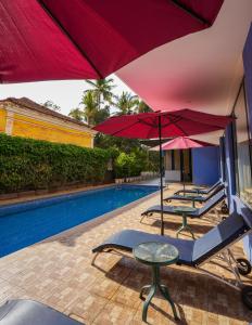 a pool with two umbrellas and a table and chairs at Rio Boutique in Candolim