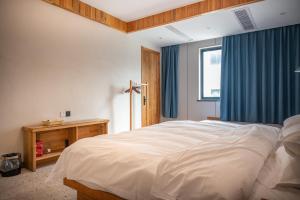 a bedroom with a large white bed and a window at Tingjian Musu Private Soup Design Homestay - South Gate of Wuzhen Xizha Scenic Area in Tongxiang