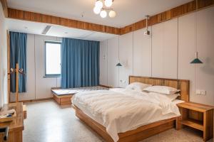 a bedroom with a large bed and blue curtains at Tingjian Musu Private Soup Design Homestay - South Gate of Wuzhen Xizha Scenic Area in Tongxiang