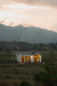 une petite maison dans un champ avec des montagnes en arrière-plan dans l'établissement Northland Pai, à Pai