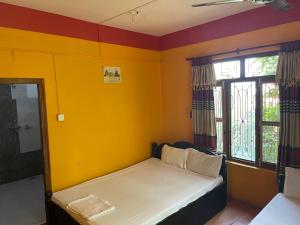 Habitación con cama con paredes y ventanas de color amarillo. en Tara guesthouse - Sauraha,Chitwan, en Sauraha