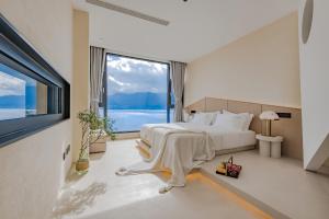 a bedroom with a large bed and a large window at Dali Oriental Seaview Hotel -Dali Erhai in Dali