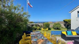 a wooden table and chairs on a patio with the ocean at Sunset Beach House Porthleven in Porthleven