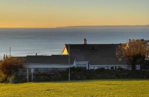 a house on a hill with the ocean in the background at Sunset Beach House Porthleven in Porthleven