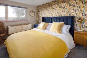 a bedroom with a large bed with a blue headboard at Sunset Beach House Porthleven in Porthleven