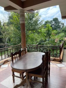 een houten tafel en stoelen op een balkon met bomen bij Tara guesthouse - Sauraha,Chitwan in Sauraha