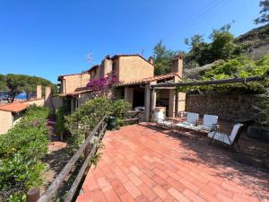 a house with a brick patio with white chairs at Villa Calypso 8 pax, waterfront with boat WiFi in Giglio Porto