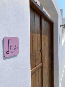 a sign on the side of a building next to a door at Pink Freud Villas Santorini in Oia +182 photos