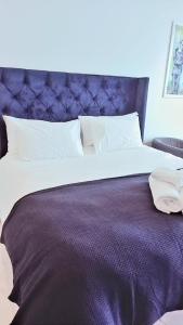 a bedroom with a large bed with a purple headboard at Sandton Skye Executive Suite-2 in Johannesburg