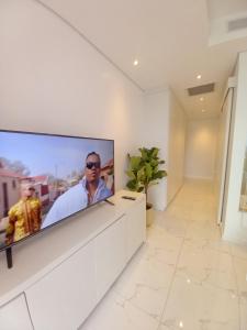 Sandton Skye Executive Suite-2 في جوهانسبرغ: تلفزيون بشاشة مسطحة كبيرة على جدار في الغرفة